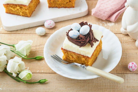 Easter carrot cake bars decorated with chocolate nest and chocolate candy eggs blossoming cherry or...
