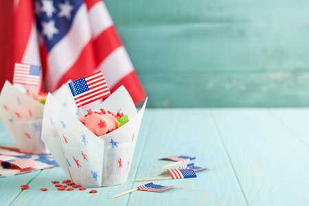Patriotic cupcake 4th July with American flag. Delicious cupcake with cream cheese and blue and red topping on old blue wooden background. Dessert food for American Independence Day celebration.の写真素材