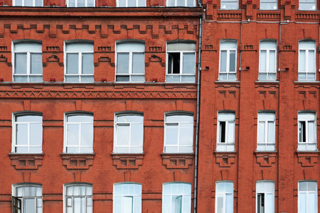Windows with white frame on red brick wall. Exterior front street view of rough vintage red brick classical facade of typical old building.の写真素材