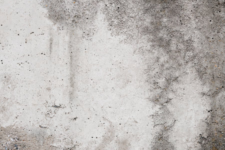 Cracked concrete wall covered with gray cement surface. Gray old wall with shabby damaged plaster or cement and brick background of an vintage dirty exfoliating plaster. Mock up.の写真素材
