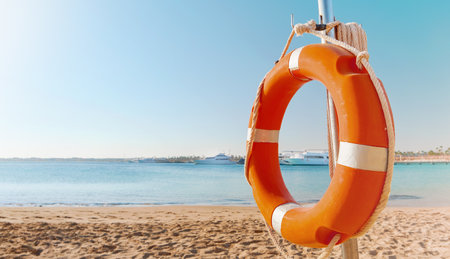 Scenic view of red and white lifebuoy on post on seaside beach. Scenery landscape of sea ocean shore on sunny day. Water rescue concept.の写真素材