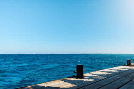 Wooden pier on sea stretching into distance beyond horizon on sunny summer day. Vacation and Travel Concept.の写真素材