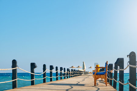 Wooden pier on sea stretching into distance beyond horizon on sunny summer day. Vacation and Travel Concept.の写真素材