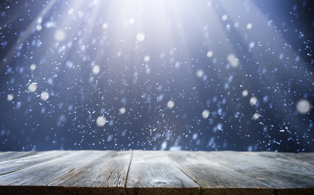 Empty old table with abstract magic snowfall and light on dark background. Holiday backdrop with dark blurred background with snow.の写真素材