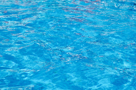 Swimming pool, ocean, sea surface abstract background. Blue water with ripples on the surface. Water waves with shining pattern texture background. Design element.の写真素材