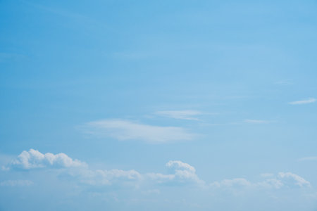 Sky. Blue sky with white clouds background. Curly clouds on a sunny summer day. Light cloudy. Good weather. Simple background sky for summer poster. Summer mock up. Soft focus.の写真素材