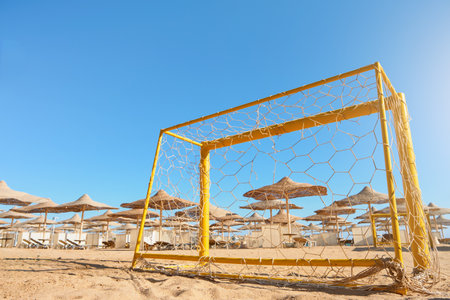 Old football goal on sandy beach on sunny day with sun rays and bokeh. Vacation and Travel Concept. Active recreation during vacation concept. Place for text.の写真素材
