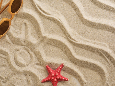 Beach sand with sunglasses, sea shells and stars, sunscreen background with natural wave pattern....