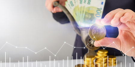 Businessman man holding bitcoin coin against stacks of gold coins and paper money coming out of old meat grinder and virtual holographic graph. Earning money, exchange, profitable, investment conceptの写真素材