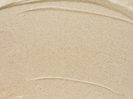Beach sand background with natural wave pattern. Summer background of beach sand with small stones along the edges. Tourism, vacation and holidays concept. Top view.の写真素材