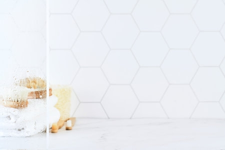 Marble table in bathroom with glass shower door with water droplets, towels, toothbrushes, sponges and body care comb in white. Minimal abstract background for product presentation. Design element.の写真素材