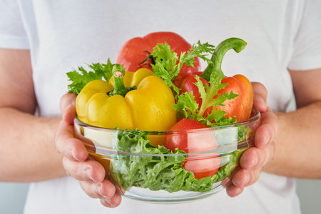 Man in white T shirt hands holding pepper, tomato, lettuce in glass plate. Healthy lifestyle, nutrition and dieting concept background. Element for design.の写真素材