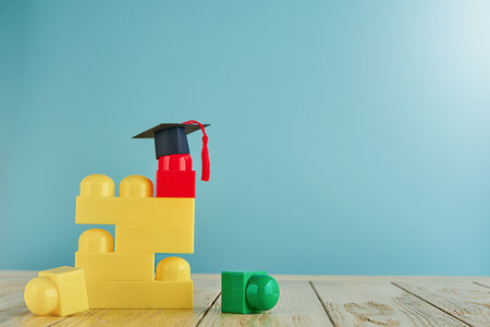 Multicolored construction cubes for children and black and masters cap or an oxford cap on blue background. Concept education, development and learning. Empty background. Back to school concept.の写真素材