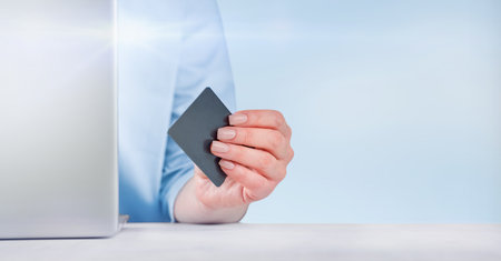 Woman or businesswoman working at laptop and holds black credit cardwith in office. Design element. Place for text.の写真素材