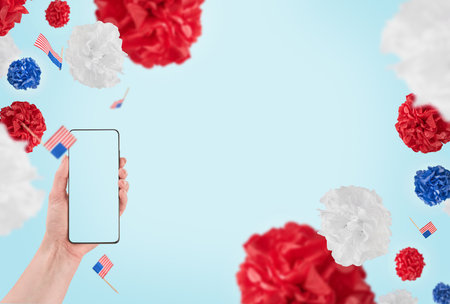 Female hand holding smartphone with blank screen for text or product background USA flag. Labor day, 4th of July, memorial day holiday concept. Design element.の写真素材