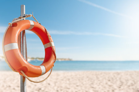 Lifebuy circle. Scenic view of red and white lifebuoy on post on seaside beach. Scenery landscape of sea ocean shore on sunny day. Water rescue concept.の写真素材