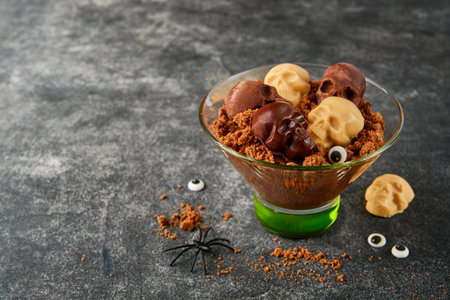 Halloween party chocolate puddings or Panna Cotta with brownie crumbles and chocolate sculls served in clear glass on gray dark background. Party idea for Halloween.の写真素材