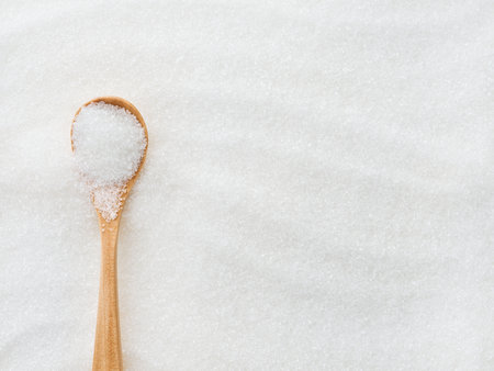 White sugar, painted waves and wooden spoon textured background with space for text. Close up.の写真素材