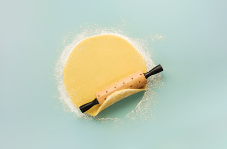Raw dough rolled out with rolling pin isolated on blue background. Top view of homemade pie crust on table. Home baking concept. Design element.の写真素材