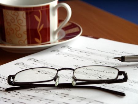 Place of employment of a music teacher. Glasses on the songbook and cup of coffee in the background. の写真素材