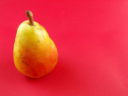 Ripe red pear on the red background の写真素材