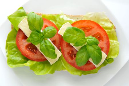 The sandwich of lettuce, the tomato, Camembert cheese and with fresh basil.の写真素材