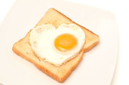 Piece of toast with the egg in the shape of a heart.の写真素材