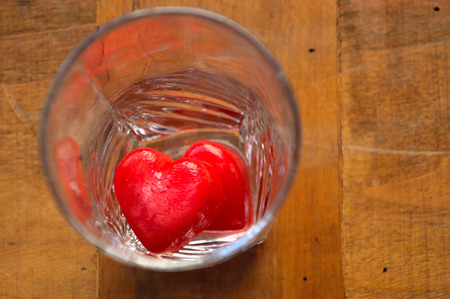 Red ice cubes in shape of hearts in a glassの写真素材
