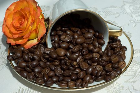 Coffee beans in white fallen retro cup with orange roseの写真素材