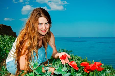 Beautiful girl with the field colors on a background an evening seaの写真素材