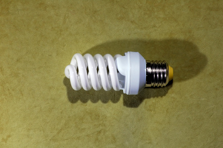 A shiny spiral fluorescent light bulb with highlights and a silvertone base, on a green backgroundの写真素材