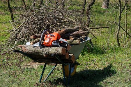 chainsaw on a wheelbarrow with firewoodの写真素材