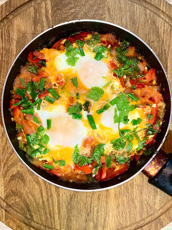 scrambled eggs with fresh vegetables and herbs in a frying panの写真素材