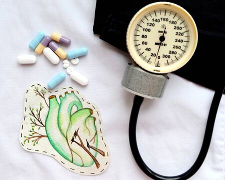 Tonometer, pills and heart in colors on the table. Cardiology.