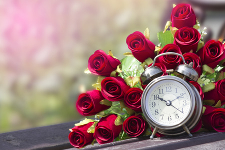 clock and bunch of red roses on backgroundの写真素材