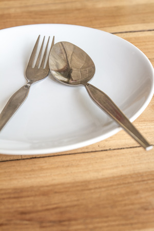 Spoon and fork on white round plateの写真素材