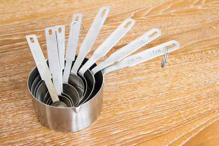 steel measuring cups on wooden tableの写真素材