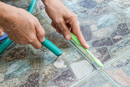 woman hand cleaning floor tiles using brush