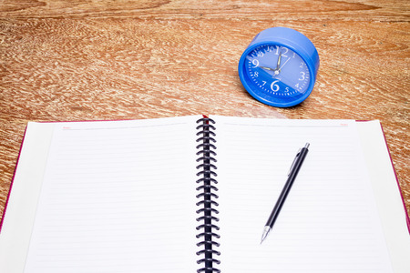 blue alarm clock and notebook on table, business concept