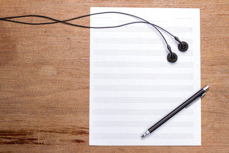 blank sheet music on wooden table with headphones and penの写真素材