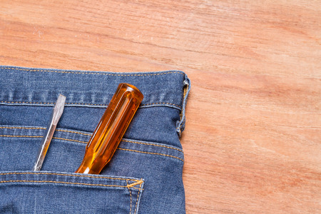 screwdriver in denim jeans pocket on wood backgroundの写真素材