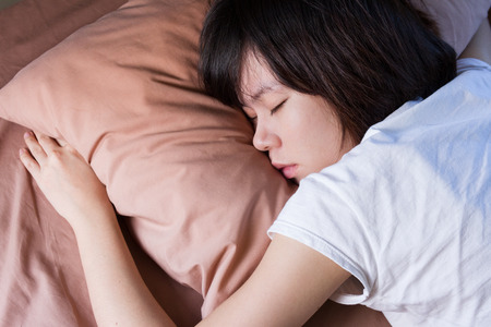 young woman sleeping in bedroomの写真素材