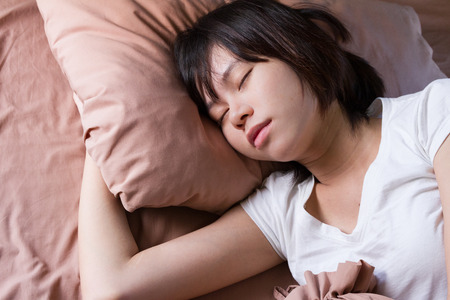 young woman sleeping in bedroomの写真素材