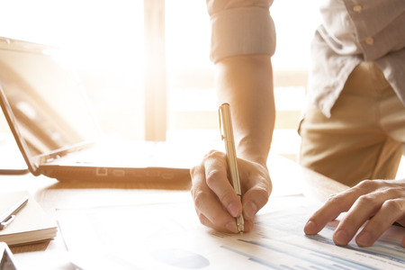 business man analyzing graph and chart document on office deskの写真素材