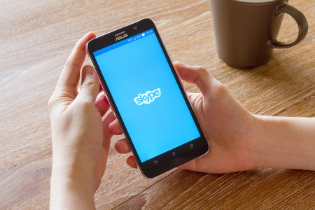 CHIANG MAI, THAILAND - APR 26, 2016: man hand holding screen shot of Skype application showing on...