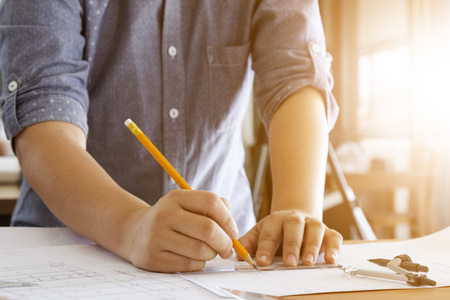 architect working and sketching architectural drawing plan on table in office