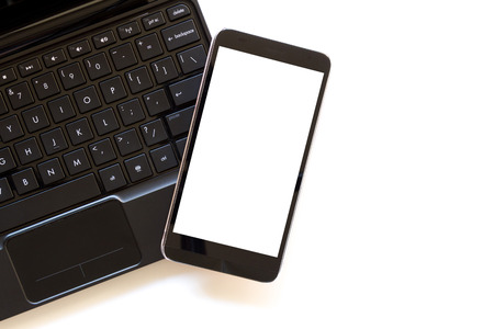 mobile phone with blank white screen on laptop computer and white backgroundの写真素材