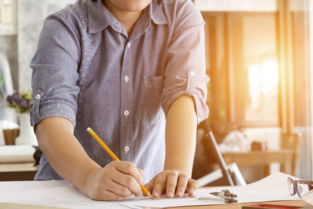 architect working and sketching architectural drawing plan on table in office