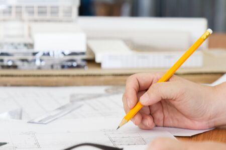 architect working and sketching architectural drawing plan on table in office