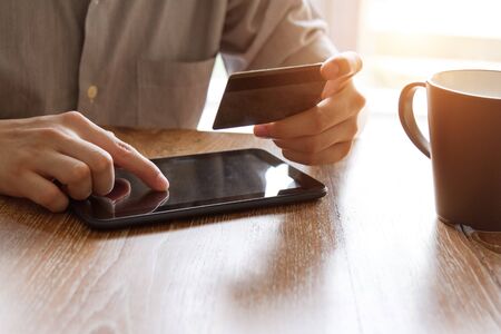 hand holding credit card and using digital tablet for online shoppingの写真素材